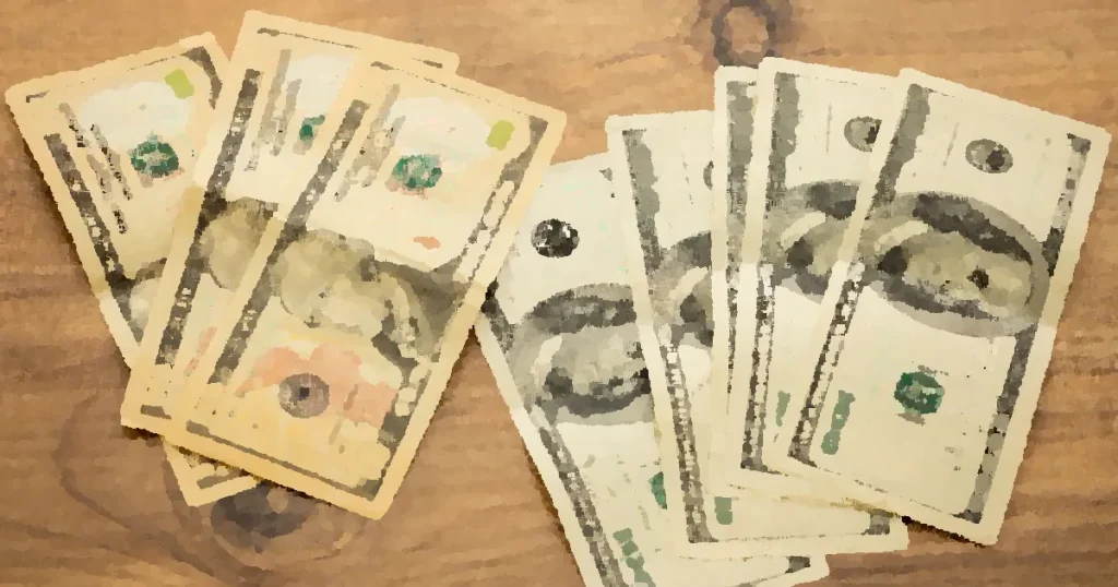 A collection of US dollar bills arranged on a wooden surface, showcasing currency denominations.