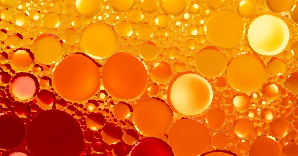 From above of vibrant glistening red and orange rings on colorful liquid surface in light of lamps
