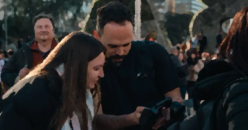 Two photographers review images on a camera display in an outdoor urban setting.