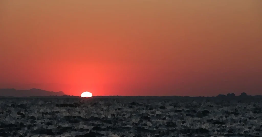 Beautiful sunset over the ocean with a mesmerizing red sky, perfect for serene and peaceful moments.