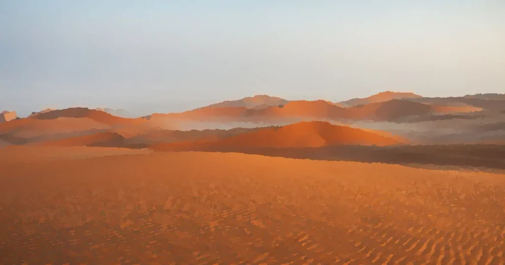 Expansive desert landscape with golden sand dunes illuminated by sunrise, showcasing natural patterns and tranquility.