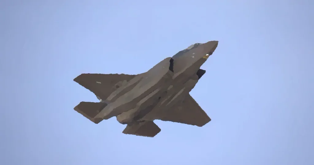 A military jet soaring through a clear blue sky, captured from below, showcasing its sleek design.
