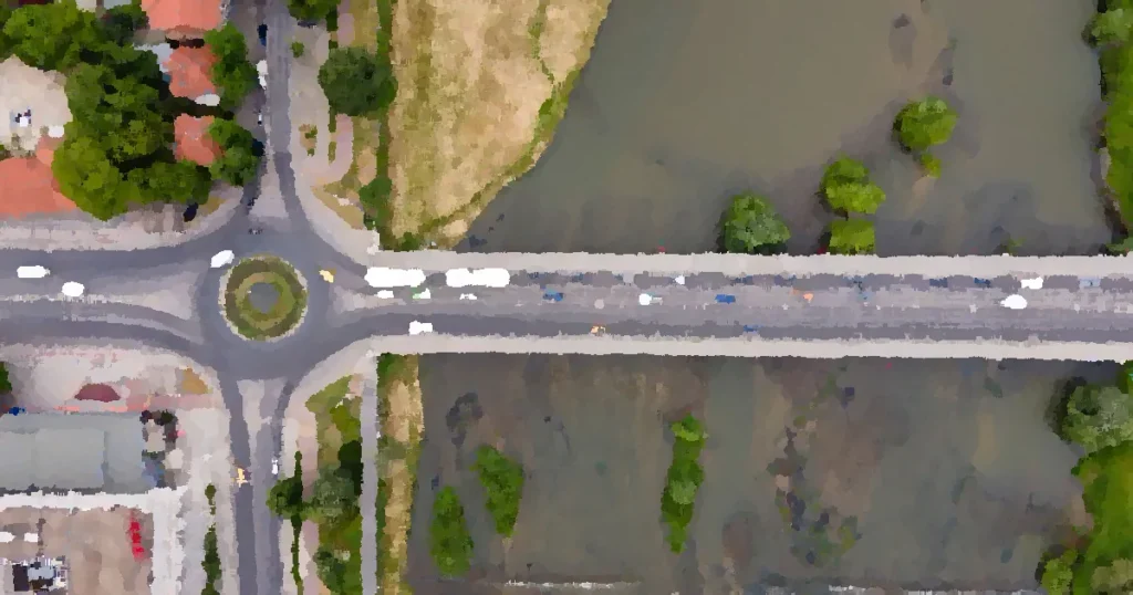 Drone shot of a busy bridge and roundabout in Plovdiv, Bulgaria with green landscapes and river.