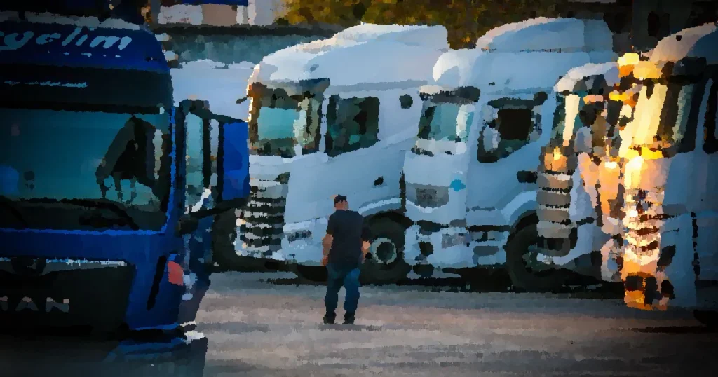 A man walks among parked trucks at sunset in an industrial area, creating a serene yet busy scene.
