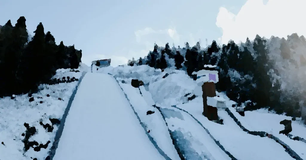 Image of a winter ski jump surrounded by snowy trees in a mountain landscape.