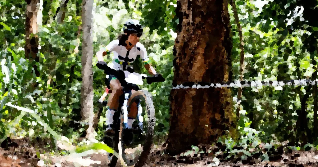 Female cyclist on mountain bike racing through a forest trail on a sunny day.