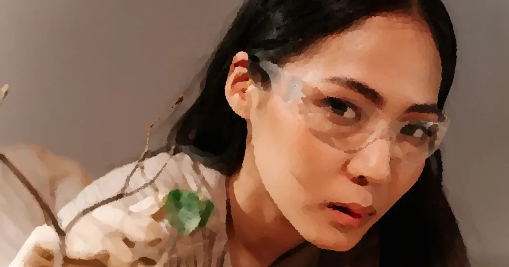 Portrait of a young woman in safety glasses studying a plant indoors.