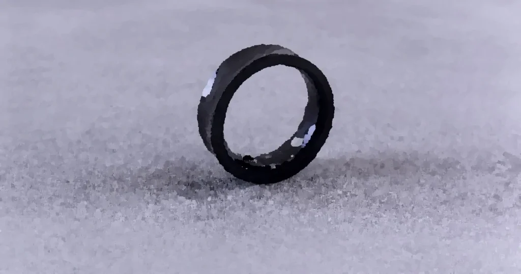 A modern black smart ring with visible circuitry resting on a textured concrete surface.