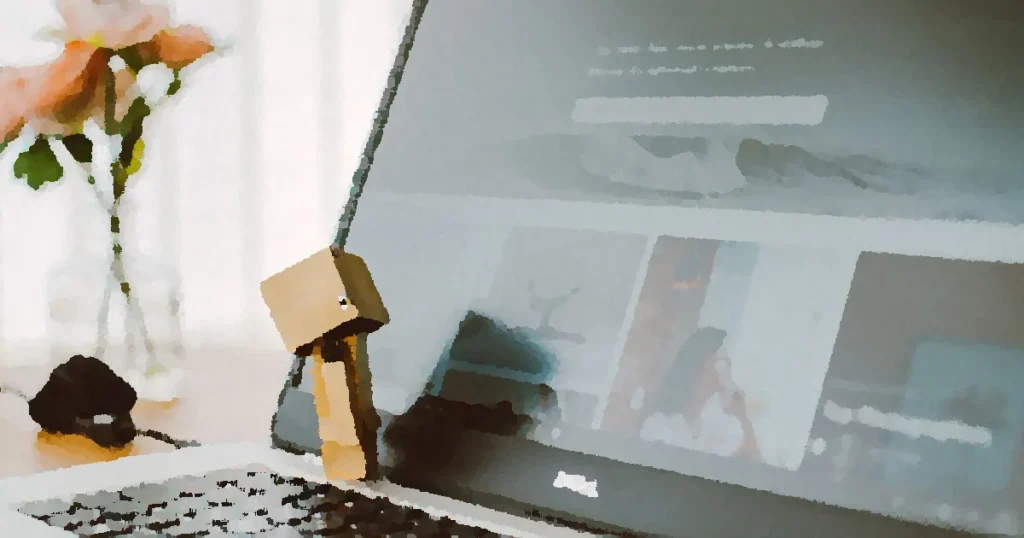 A small toy figure stands on a laptop keyboard with flowers in the background.
