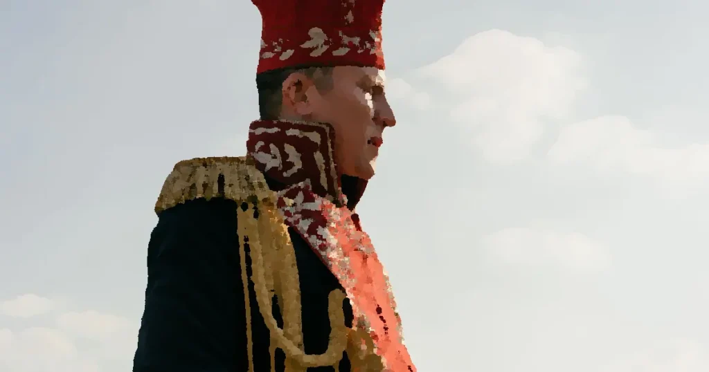 Side profile of a man wearing ornate historical military uniform outdoors.