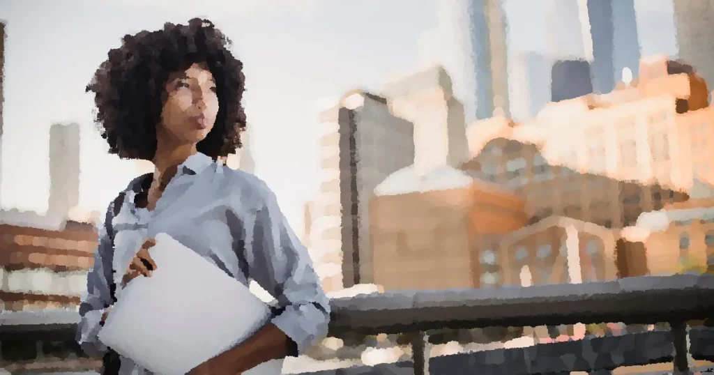 Confident woman in business attire holding a laptop in an urban outdoor setting.