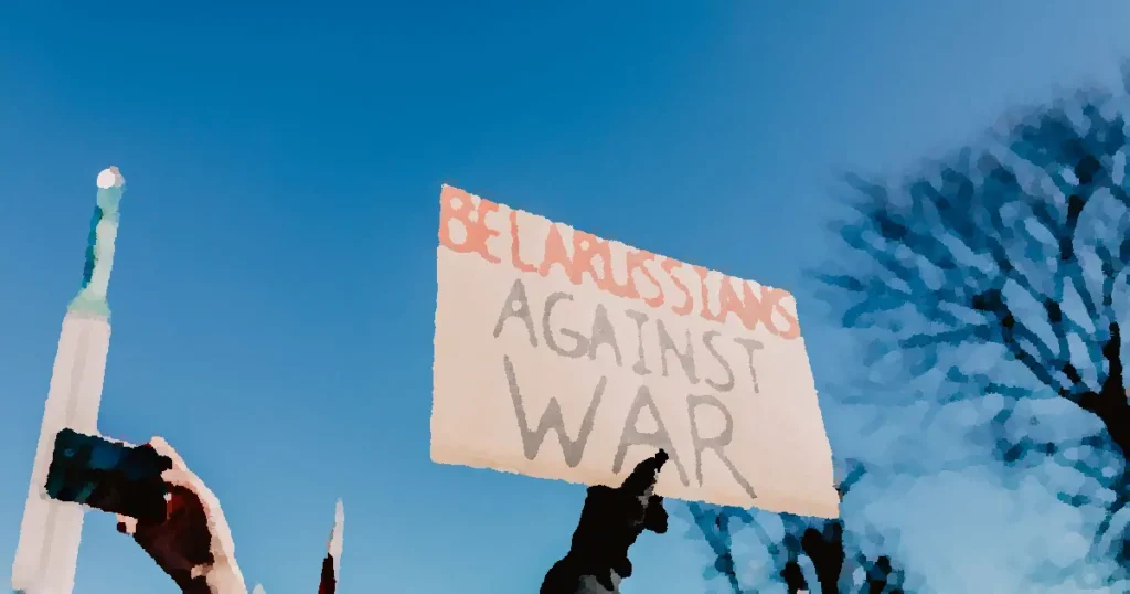 Demonstrators in Riga holding a sign 'Belarussians Against War.' Clear blue sky.