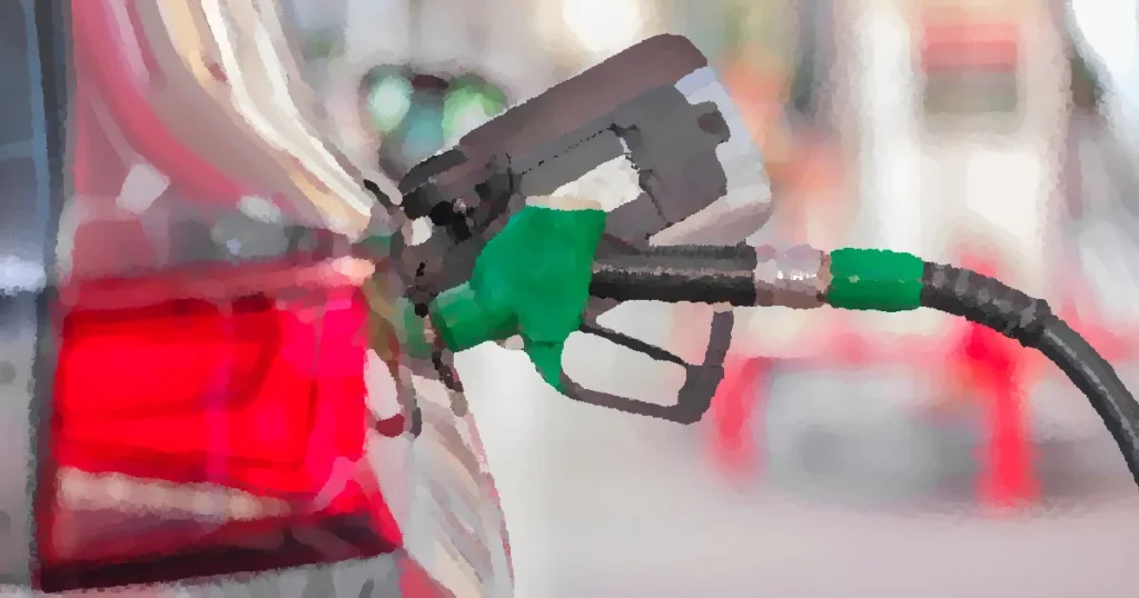A close-up view of a fuel pump nozzle inserted into a car's tank at a gas station.