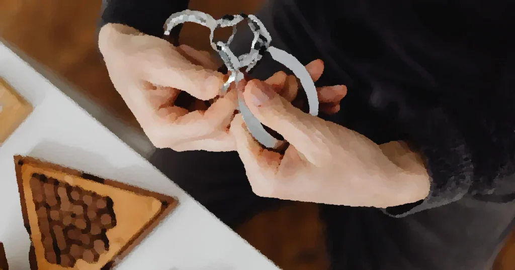 Person carefully handling silver handcuffs indoors, close-up view.