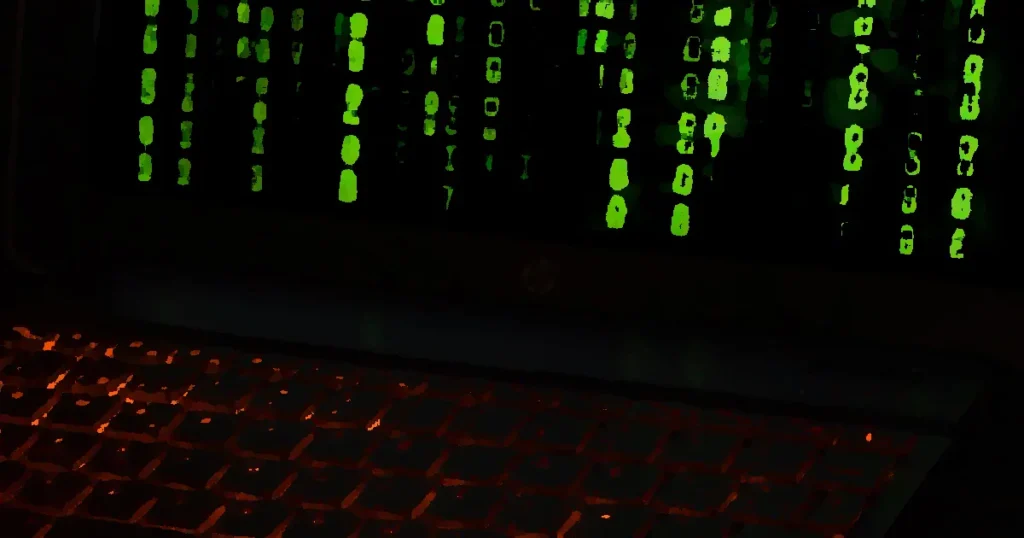 A laptop keyboard with orange backlight displaying green digital code symbols.