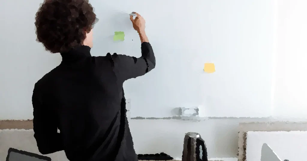 Professional man planning strategy on a whiteboard in a modern office setting.