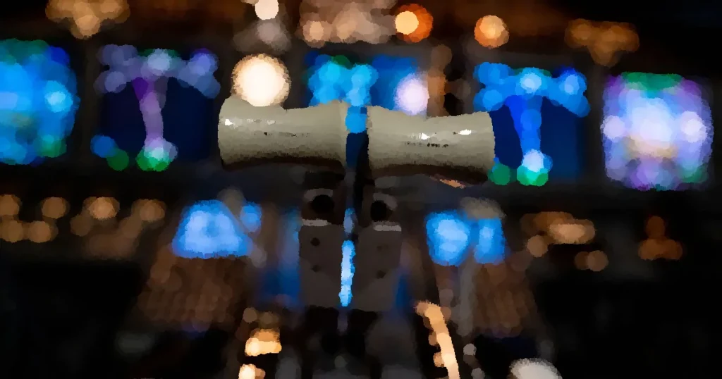 Close-up of airplane cockpit controls with illuminated electronic display panels.