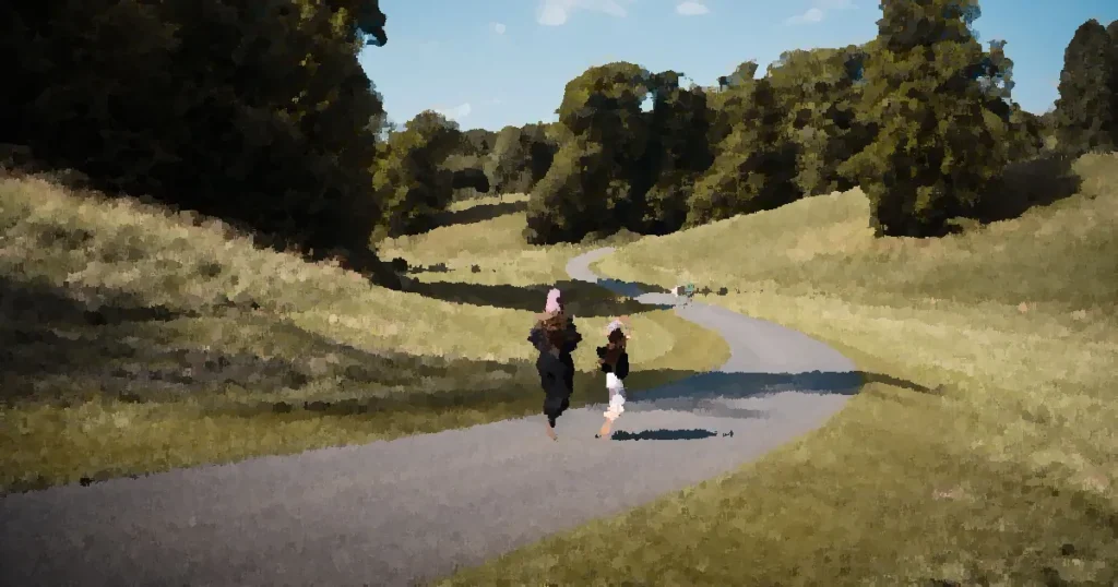 Two people walking on a scenic pathway in Woodstock, UK, surrounded by lush greenery on a bright summer day.